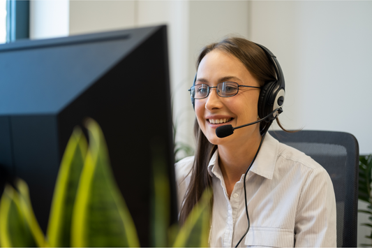 woman from BigPurpleCare Support team with headset on smiling and looking at a computer screen