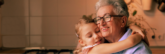 old woman and young girl hugging in warm kitchen.
