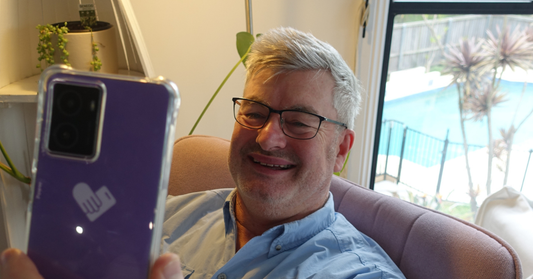 happy man looking at a bigpurplephone in his home